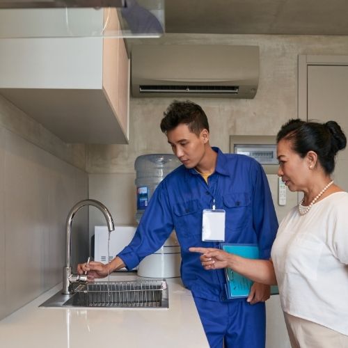 Installateur und Frau prüfen den Wasserhahn