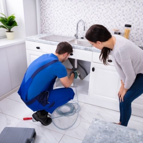 Installateur hilft Frau bei Abflussarbeiten